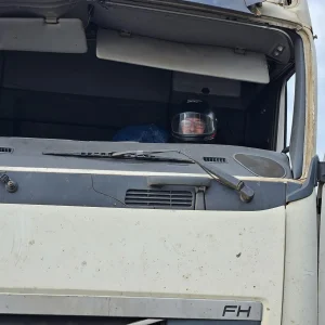 Carreta sem para-brisa, caminhoneiro de capacete, peças amarradas com cordas