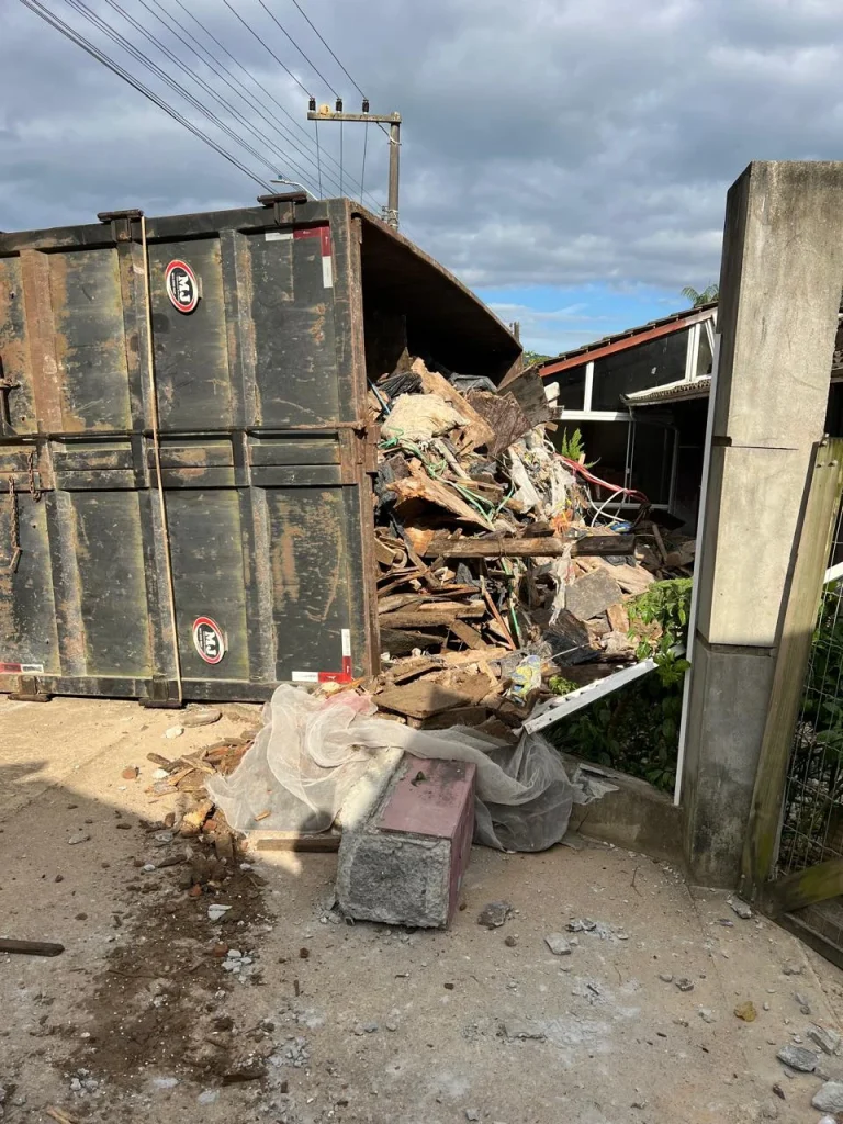 Vídeo: caminhão tomba e entulhos caem em quintal de residência, em Itajaí