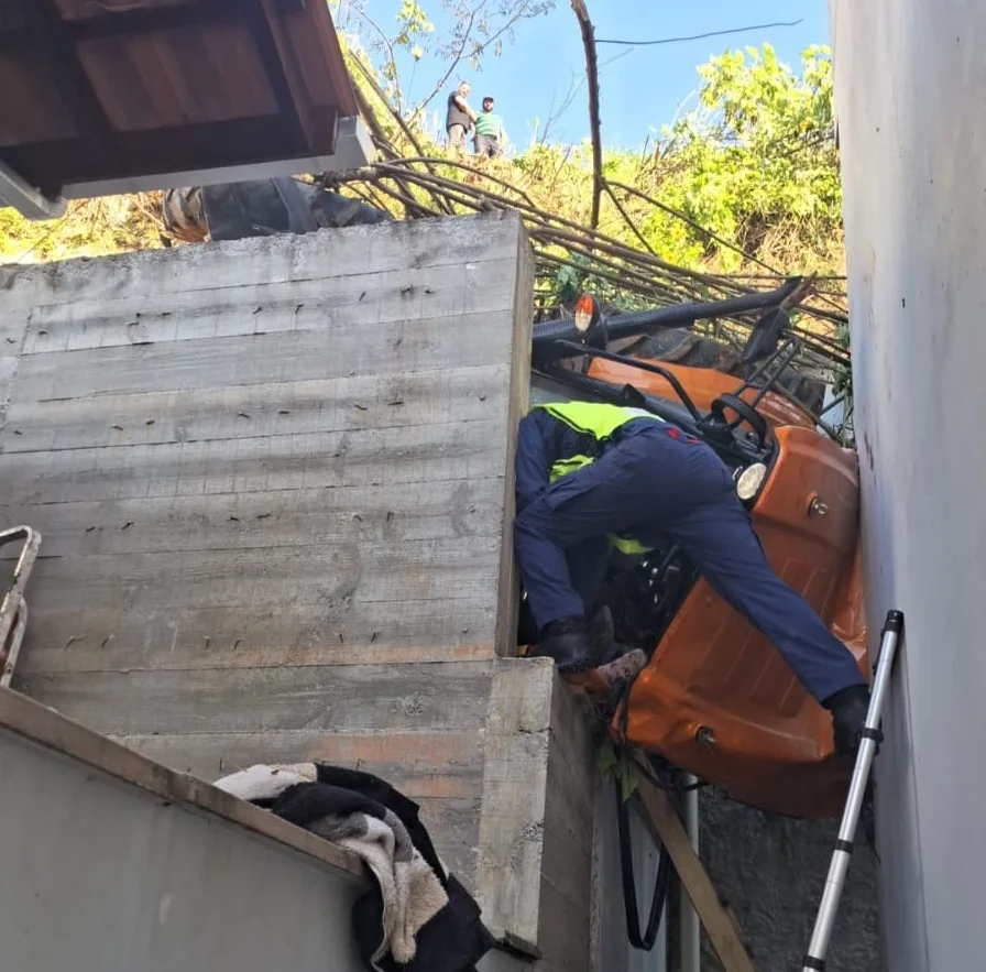 Trator desce ribanceira, atinge casa e jovem fica pendurada no veículo, em Brusque
